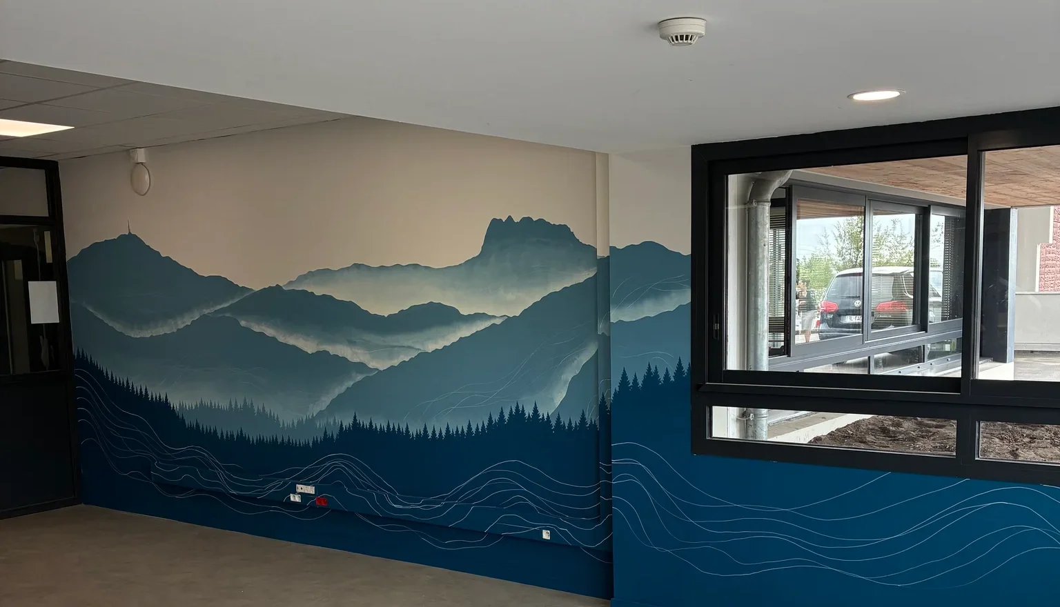 Grande fresque murale de montagnes bleues et de vagues peinte sur mesure dans un espace professionnel du Pays Basque